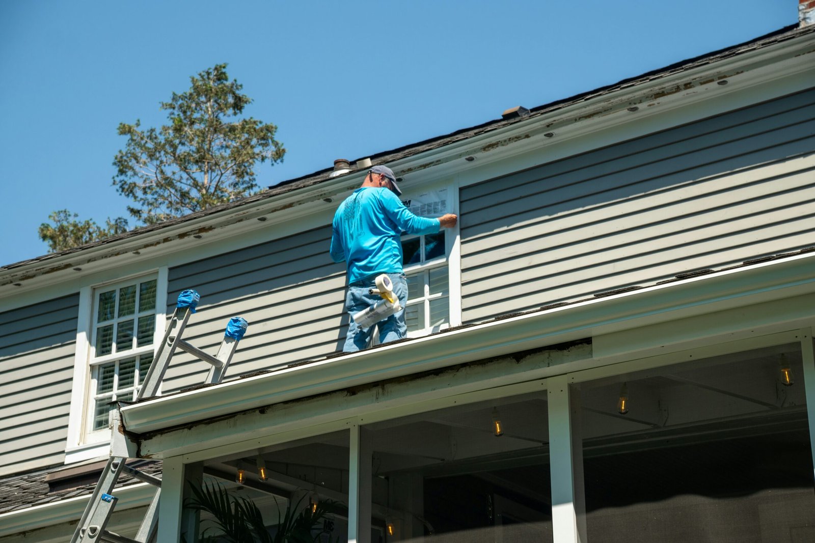 Contractor installing exterior siding around an upper-story window on a residential home.